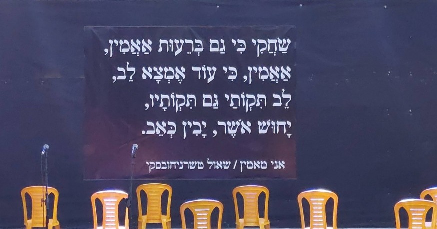 The stage at Gymnasia High School, 12/05/24; a poem by Chernichovsky about friendship and hope is projected onto it.